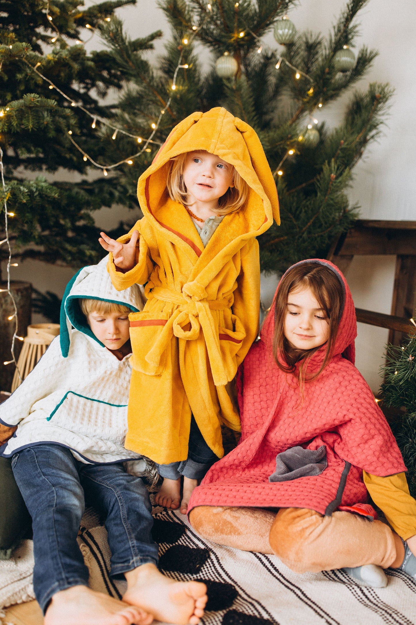 toddler in yellow bathrobe next to christmas tree